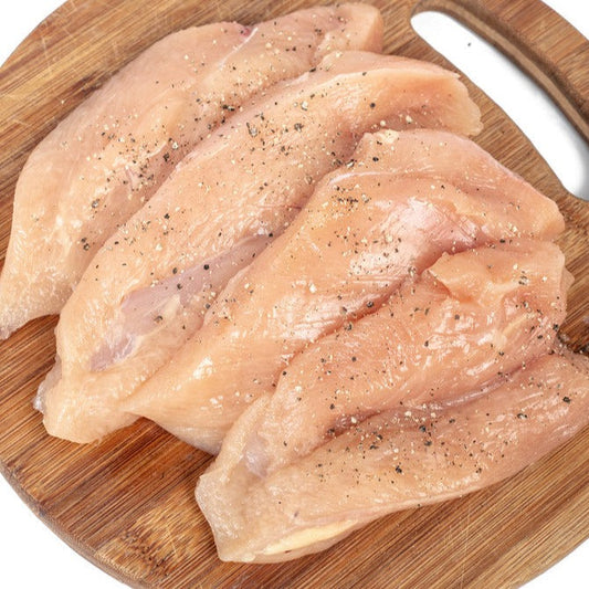 raw chicken breast slices on a wooden cutting board seasoned with salt and pepper